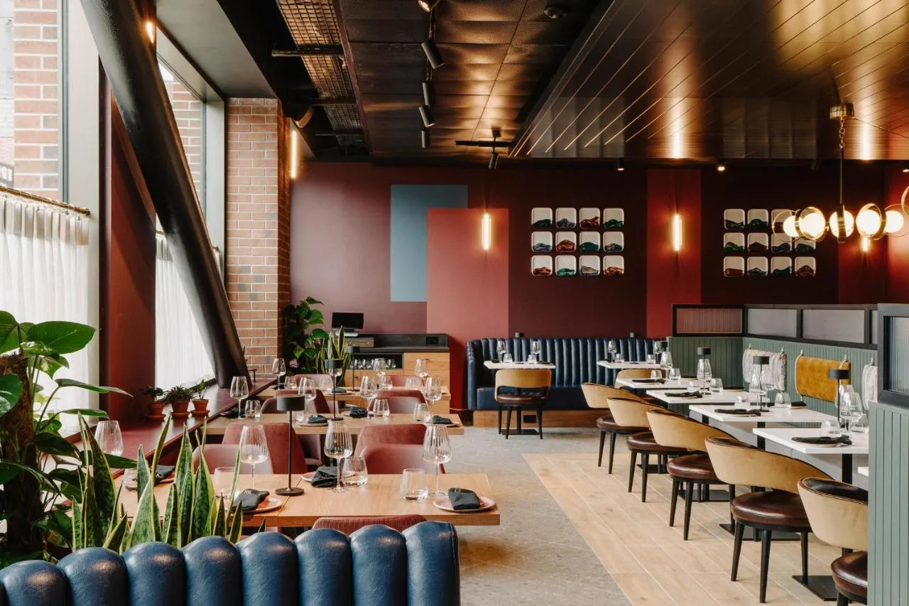 a restaurant with wooden tables and chairs and red walls at The Halyard Liverpool, Vignette Collection by IHG in Liverpool